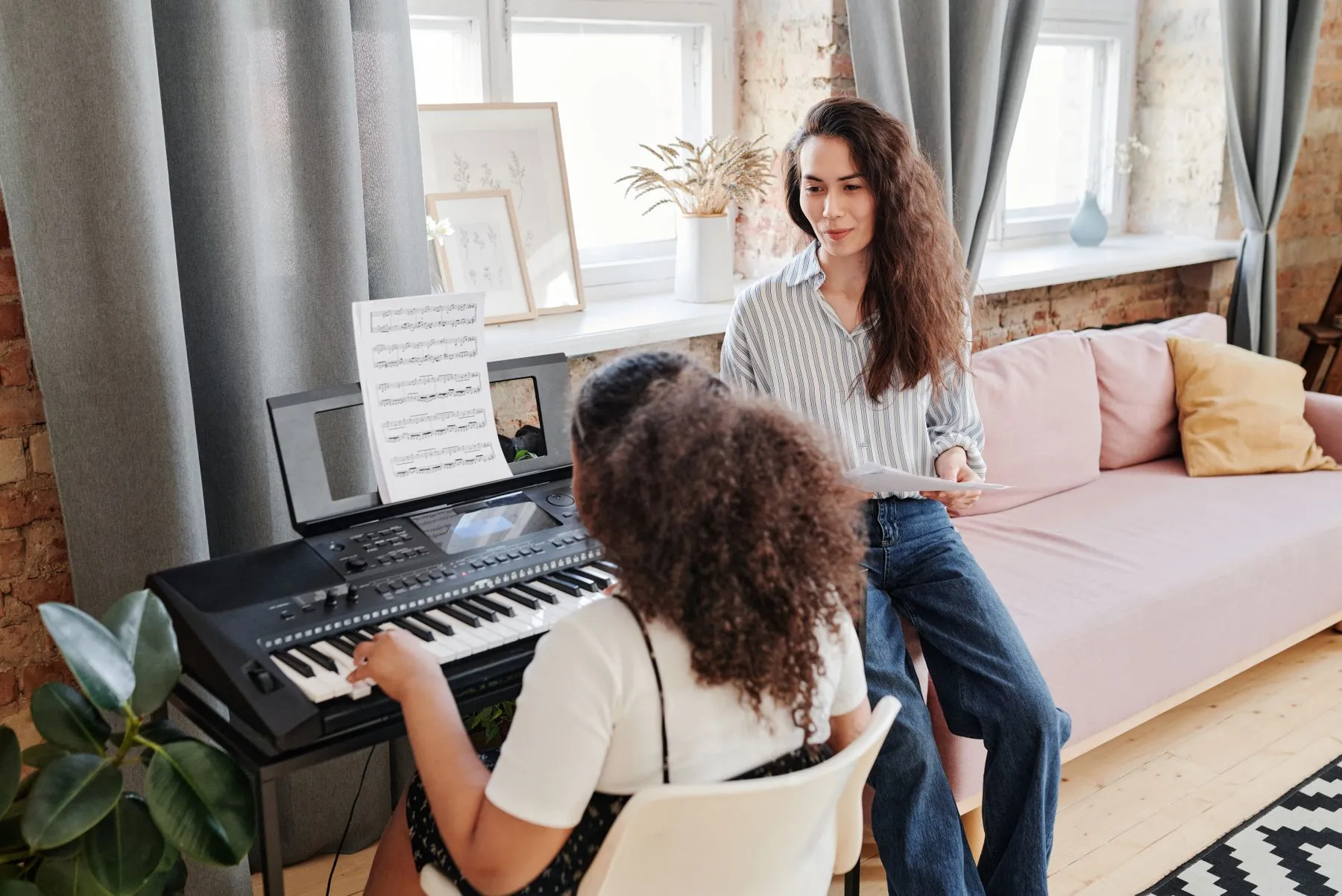 Professora acompanhando uma aluna em aula de piano