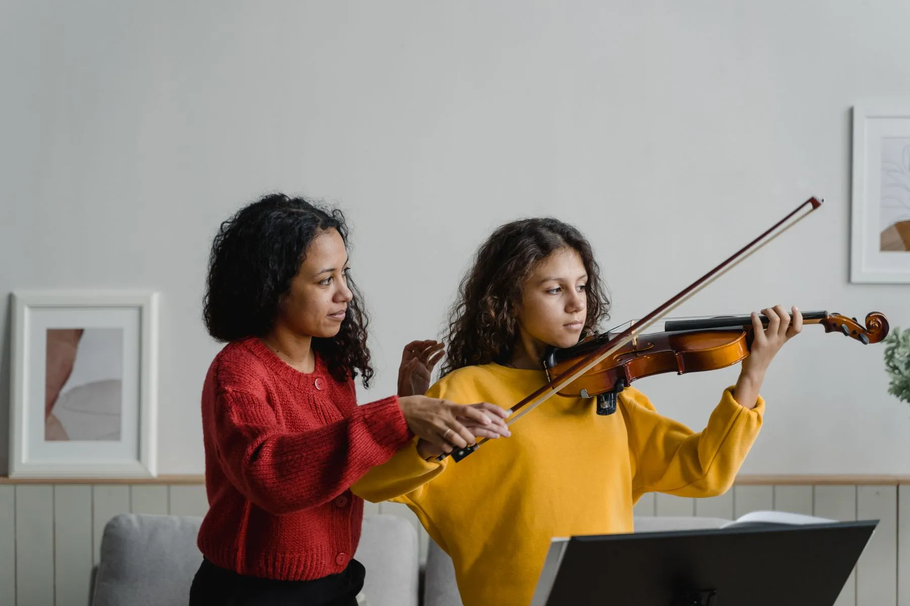 Professora ensinando violino a uma aluna